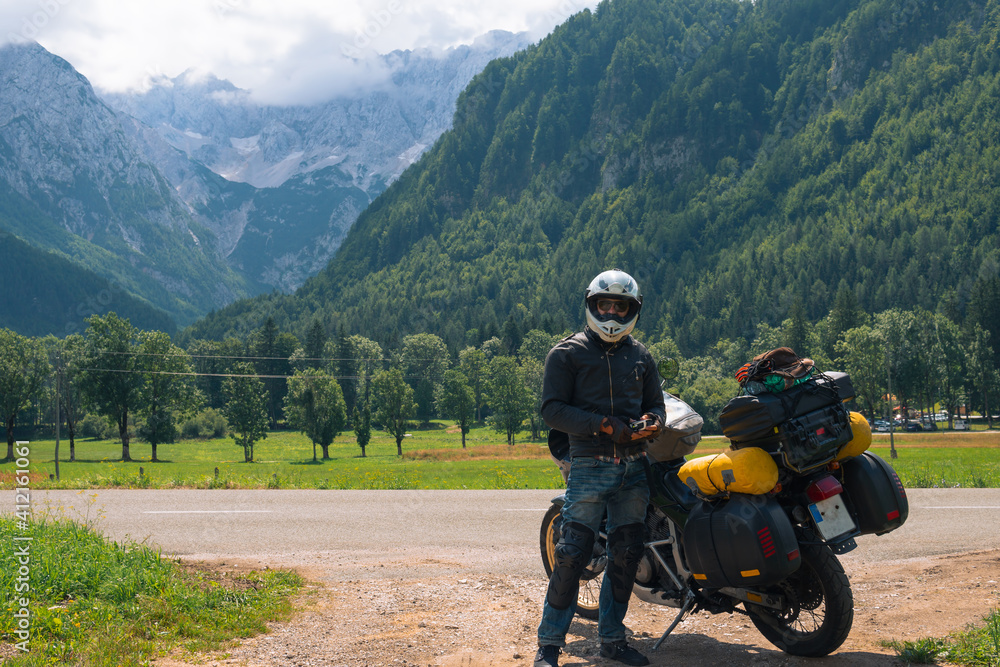 Fototapeta premium Motorcyclist man and Adventure Motorbike with bags. Motorcycle trip. World Traveling, Lifestyle Travel vacations sport outdoor concept, copy space. Zgornje Jezersko Slovenia