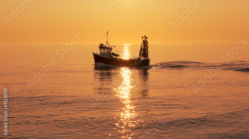 Fishing boat on a calm sea in early morning sunlight. Aldeburgh, Suffolk. UK © david