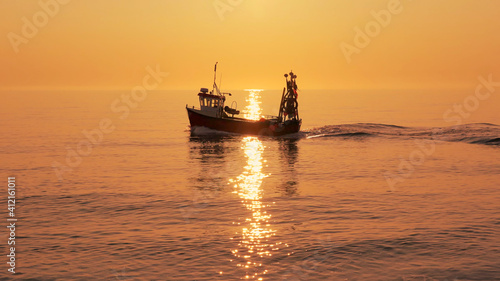 Photos Fishing boat on a calm sea in early morning sunlight