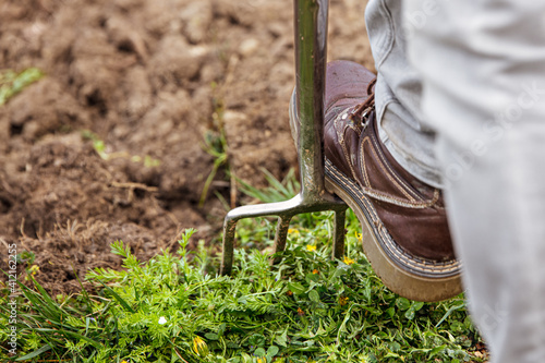 man is digging with a gardening fork in his garden photo