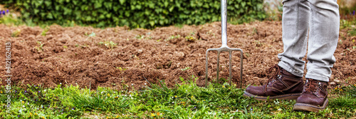 man holding a gardening fork, sticking in the ground
