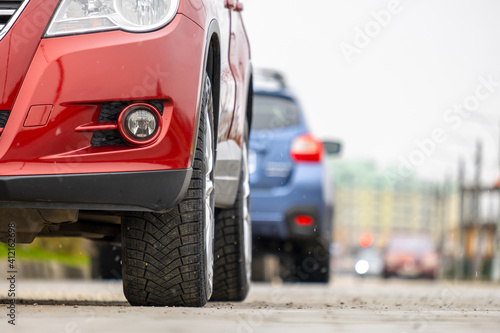 Closeup of parked car on a city street side with new winter rubber tires. © bilanol