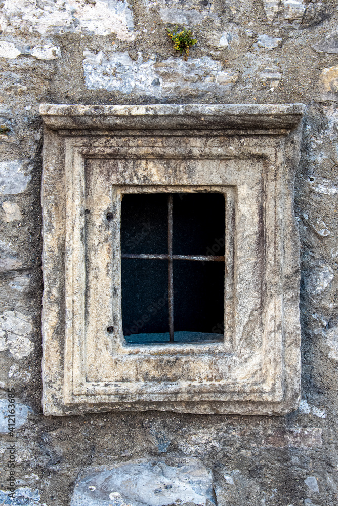old stoned window with iron bars in an old wall