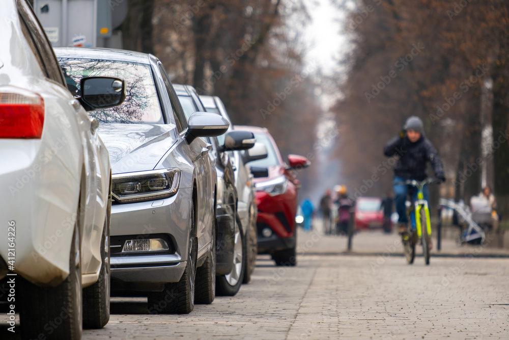 Cars parked in a row on a city street side. Cars parked in a row on a city street side.