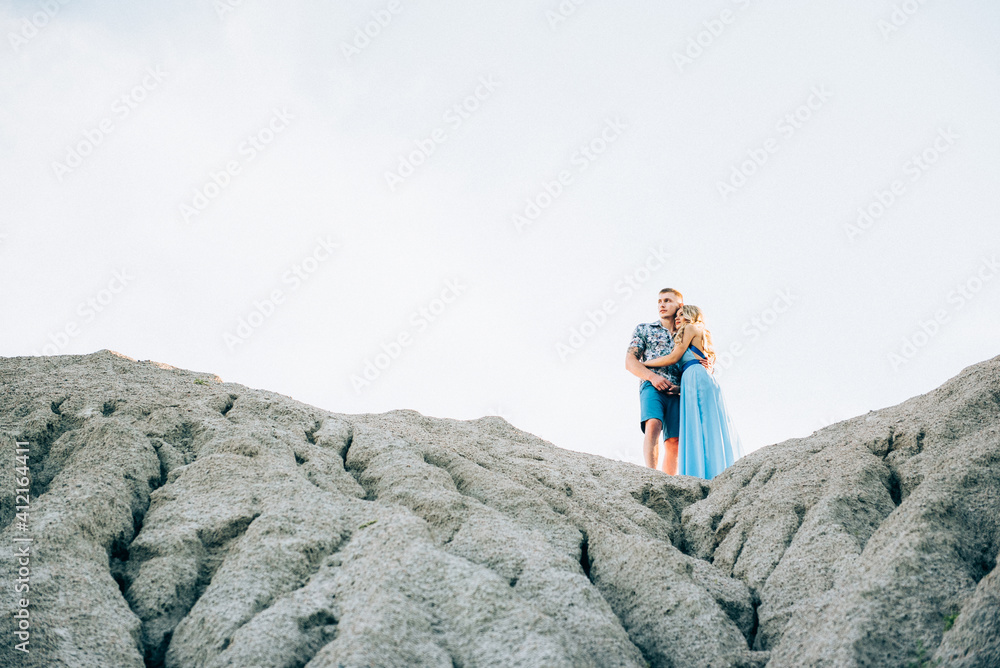blonde girl in a light blue dress and a guy in a light shirt in a granite quarry
