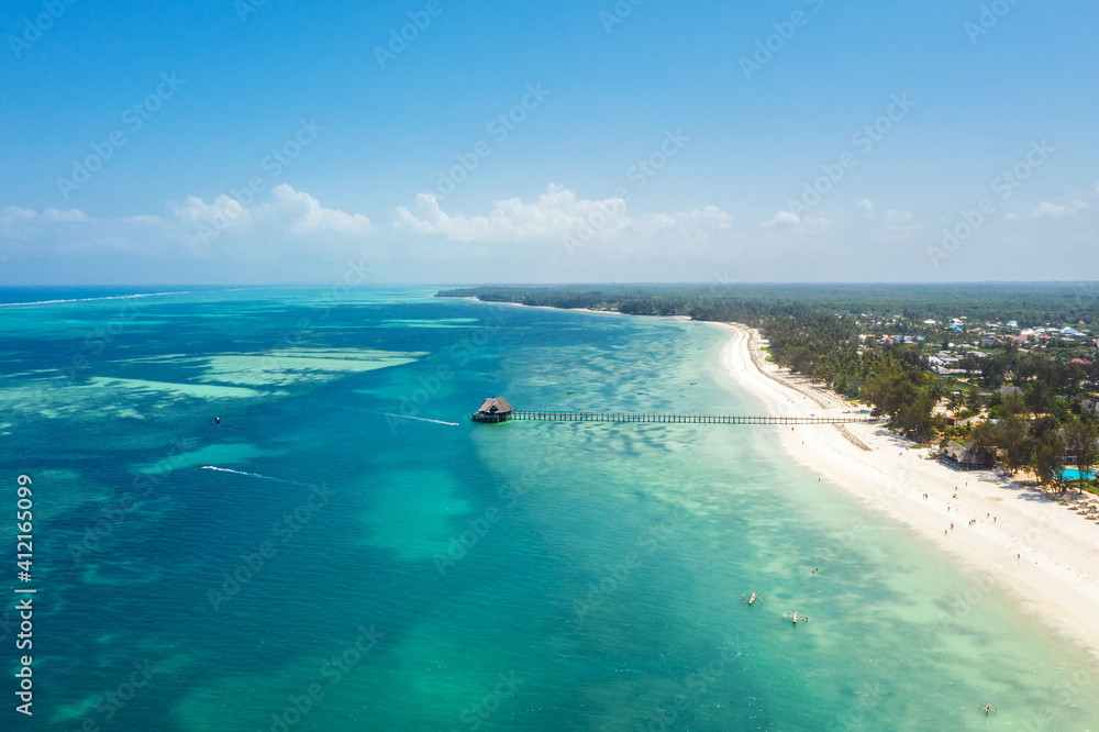 Aerial shot of Kiwengwa beach washed with turquoise Indian ocean waves. White sand sandbank beach on Zanzibar island, Tanzania. Exotic countries travel concept