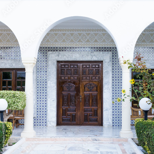 The arcade and the wooden door in the oriental style are decorated with ceramic mosaics