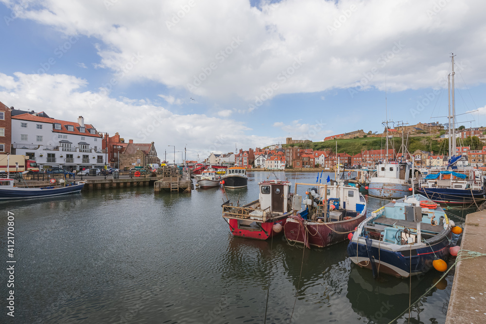 Nautical scene of fishing and sailboats at Whitby Marina in the Humber estuary along the River Esk on a sunny afternoon in North Yorkshire, England.