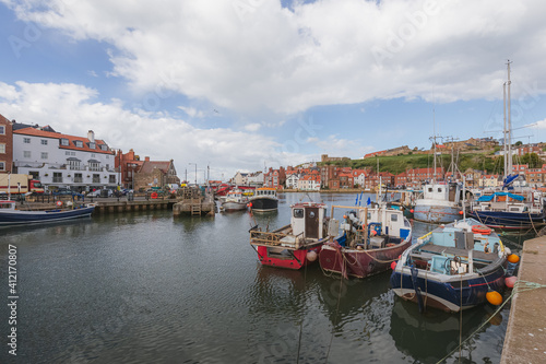 Nautical scene of fishing and sailboats at Whitby Marina in the Humber estuary along the River Esk on a sunny afternoon in North Yorkshire, England.