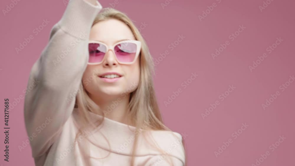 Dancing Happy Girl with Long Blonde Hair Shaking Rhythmically Moving her Hands Up Down Music in Sunglasses Smile Pink Background. Funny Dancing Teen. Fashion. Glamour Positive Emotions People. Freedom Dancing Happy Girl with Long Blonde Hair Shaking Rhythmically Moving her Hands Up Down Music in Sunglasses Smile Pink Background. Funny Dancing Teen. Fashion. Glamour Positive Emotions People. Freedom