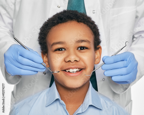 African American boy in dental clinic for children. Child with toothy smile during inspection of oral cavity by a dentist. Close-up