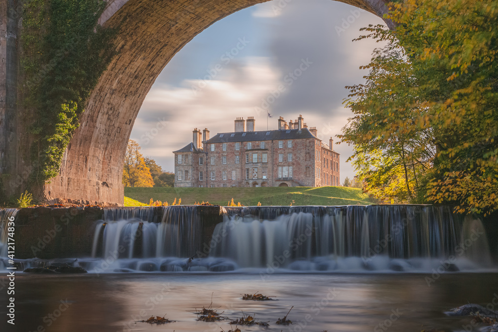 Dalkeith Country Park with waterfall and arch framing manor house on a