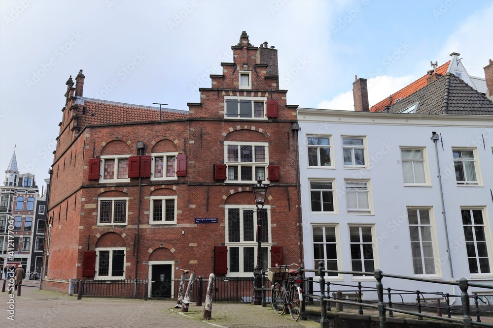 Street View in Amsterdam with Historic Brick Building with Red Shutters and Stepped Gable