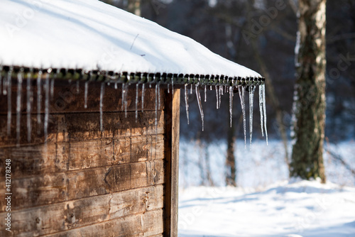 .Icicles hanging on a wooden hut, winter landscape.