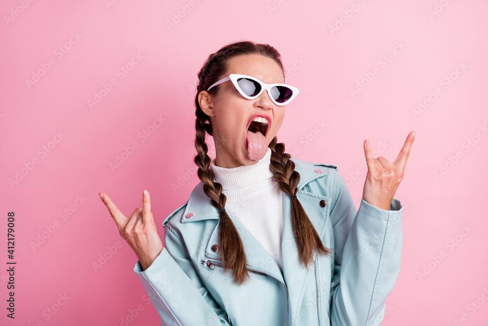 Photo of young brutal girl tongue-out show fingers rock sign music lover isolated over pastel color background Photo of young brutal girl tongue-out show fingers rock sign music lover isolated over pastel color background