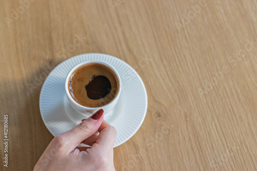 The woman on the wooden table holding Turkish coffee with your hands