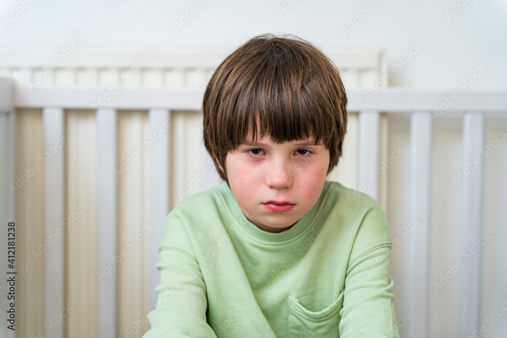 Portrait of an unhappy and sad boy of ten years old sitting alone at home. Depressed child showing emotions. Portrait of an unhappy and sad boy of ten years old sitting alone at home. Depressed child showing emotions.
