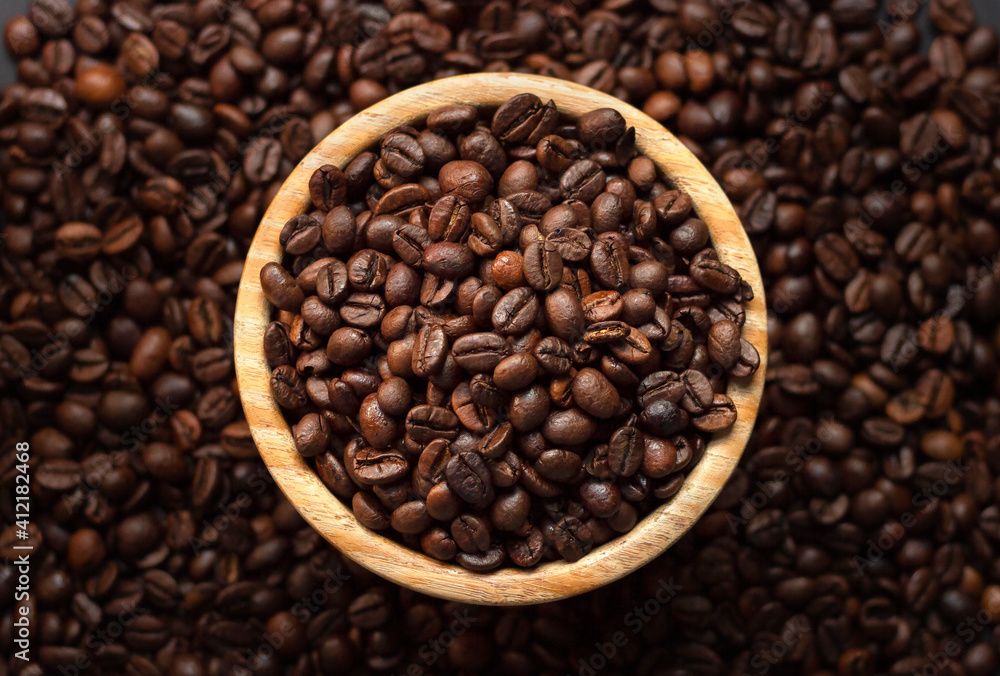 Bunch of coffee beans on a wooden bol with a coffee bean background for coffee lovers