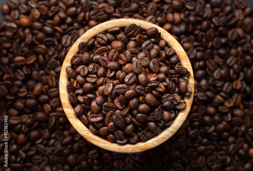 Bunch of coffee beans on a wooden bol with a coffee bean background for coffee lovers
