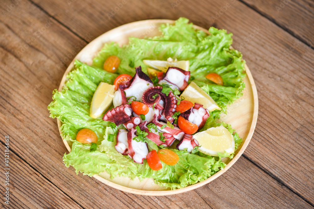 Octopus salad with lemon tomatoes and vegetables on wooden plate Fresh and healthy salad seafood squid and octopus. Octopus salad with lemon tomatoes and vegetables on wooden plate Fresh and healthy salad seafood squid and octopus.