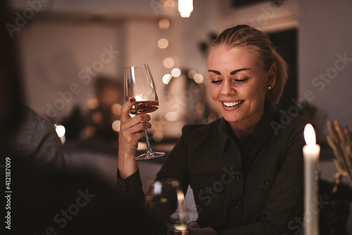 Canvas Print Smiling woman drinking wine during a candlelit dinner party