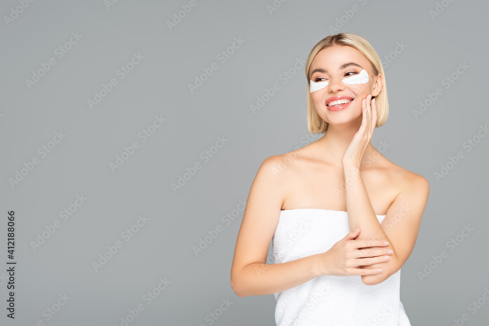 Blonde woman in towel and eye patches standing isolated on grey Blonde woman in towel and eye patches standing isolated on grey