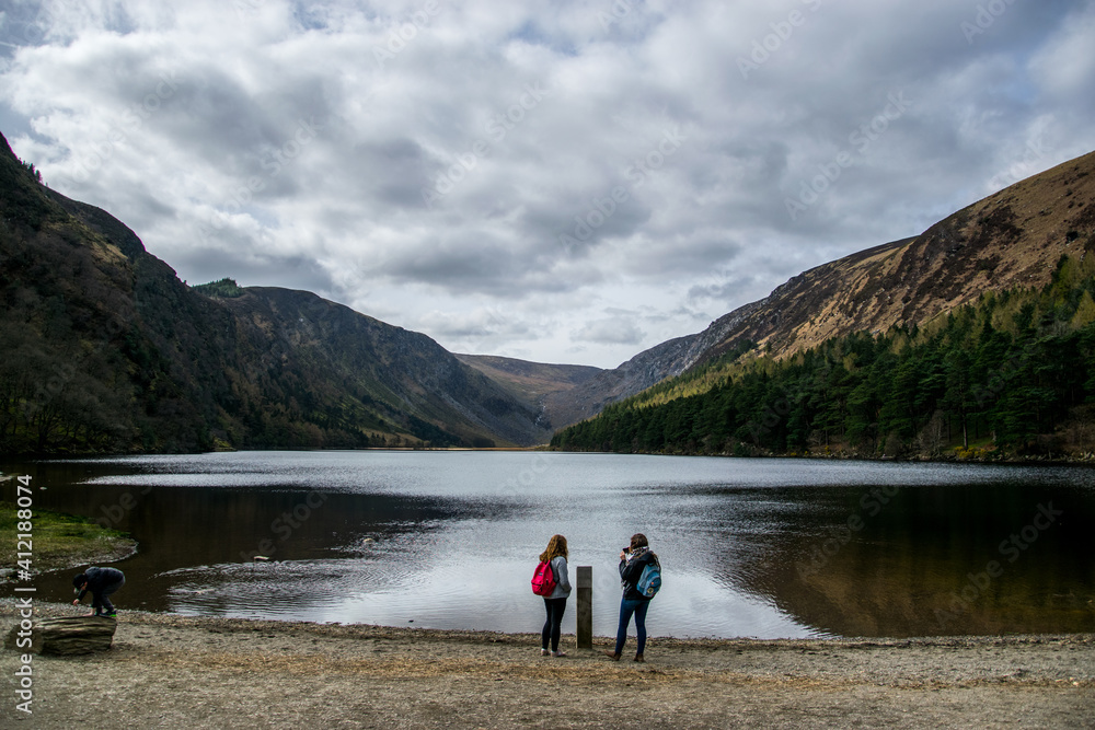 Dos jóvenes observan un lago entre colinas y con nubes que amenazan lluvia. Dos jóvenes observan un lago entre colinas y con nubes que amenazan lluvia.