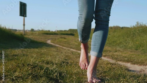 [4k] slow motion of barefeet woman in jeans walking on grass