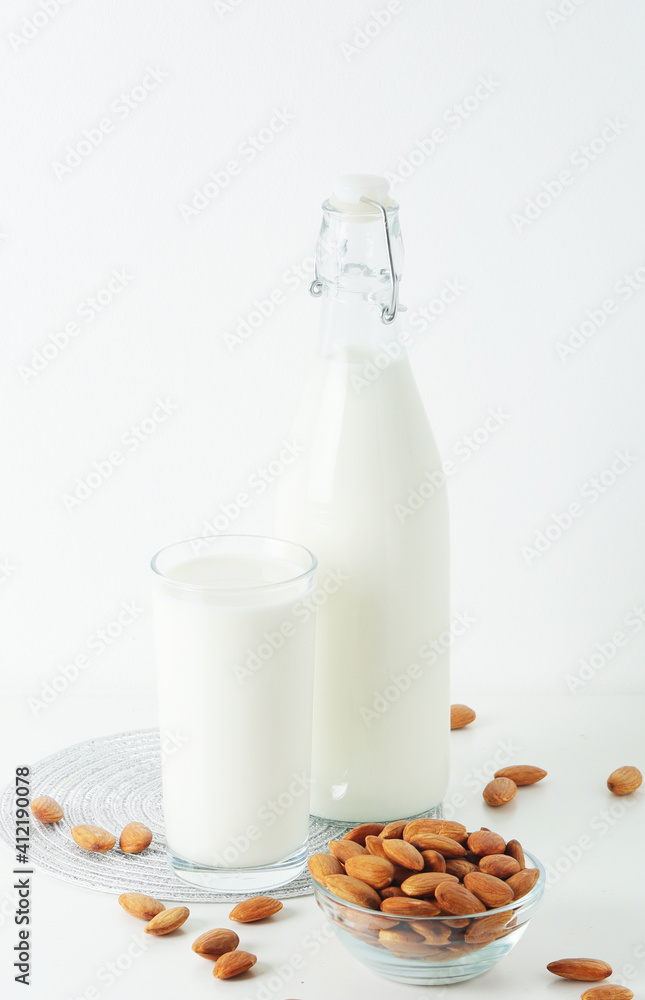 A glass with almond milk and the bowl with almonds A glass with almond milk and the bowl with almonds