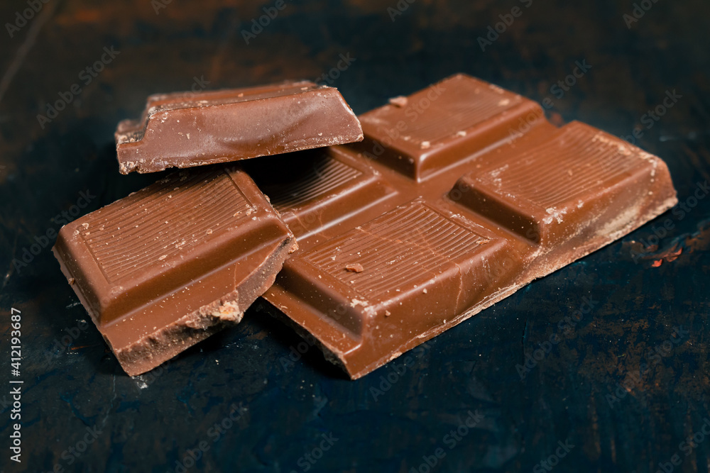 Tablet pieces of dark chocolate on a dark surface. Tablet pieces of dark chocolate on a dark surface.