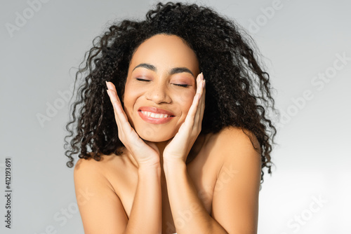 Young african american woman with perfect skin smiling with closed eyes isolated on grey