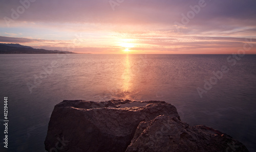 Beautiful sunrise on the sea with rocks in the foreground. Views from Torre del Mar beach.