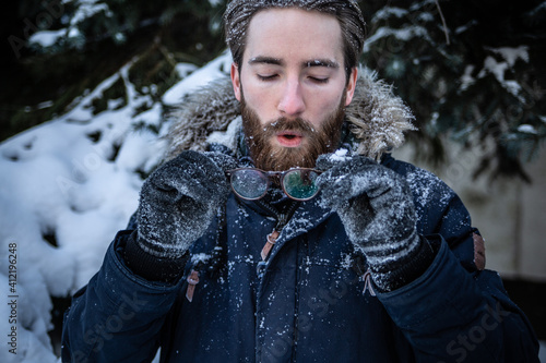 Cuadro en lienzo Man sprinkled in snow, cleaning fogged up glasses on a winter sunny day
