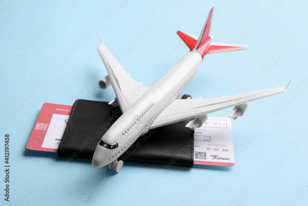 Toy airplane and passport with ticket on light blue background Toy airplane and passport with ticket on light blue background
