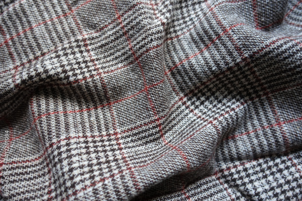 White, grey and red Glen check woolen fabric in soft folds White, grey and red Glen check woolen fabric in soft folds
