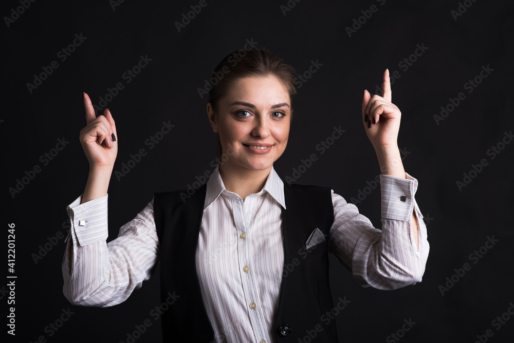 Portrait of a businesswoman pointing her fingers up in the studio on a black background Portrait of a businesswoman pointing her fingers up in the studio on a black background