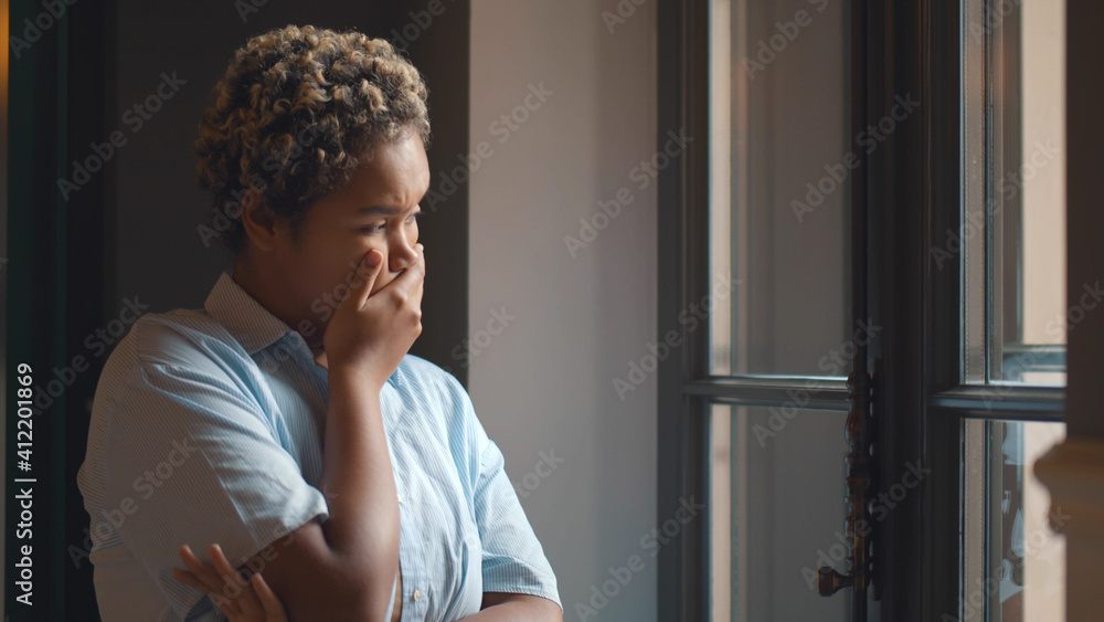 Young worried afro-american woman looking out of window Young worried afro-american woman looking out of window