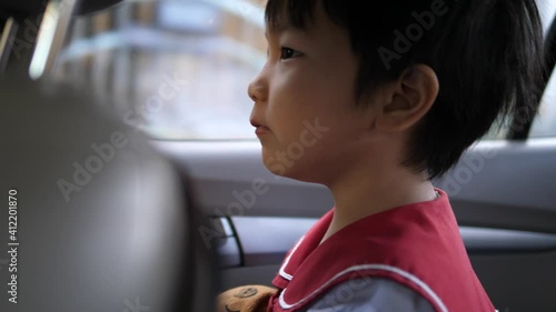 4K Asian kindergarten child boy watching outside from car window with happy relax face before back to school in morning. Concept of family lifestyle, transportation.