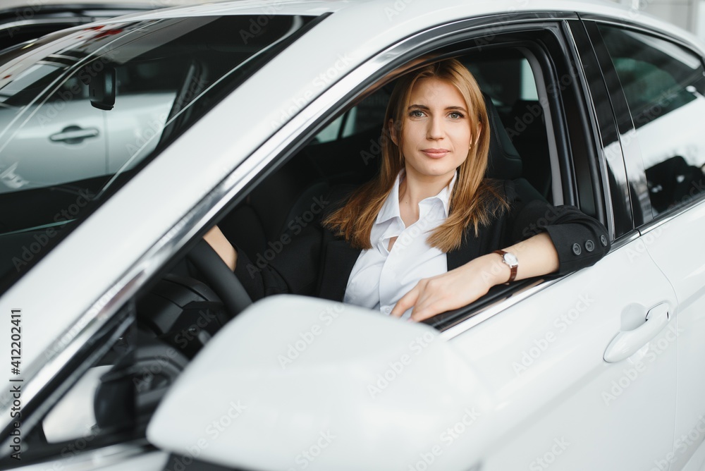Young beautiful woman showing her love to a car in a car showroom Young beautiful woman showing her love to a car in a car showroom