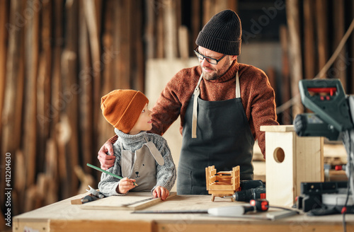 Father and son making bird house in workshop photo