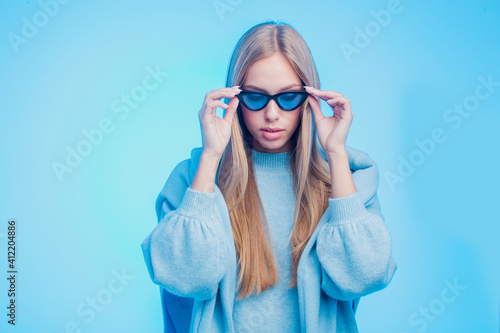 Fashion shot of young model wearing blue sunglasses and clothes
