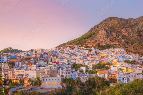 A scenic sunset or sunrise cityscape view over Chefchaouen, Morocco, known as the Blue Pearl with its shades of blue on the town's historic buildings.