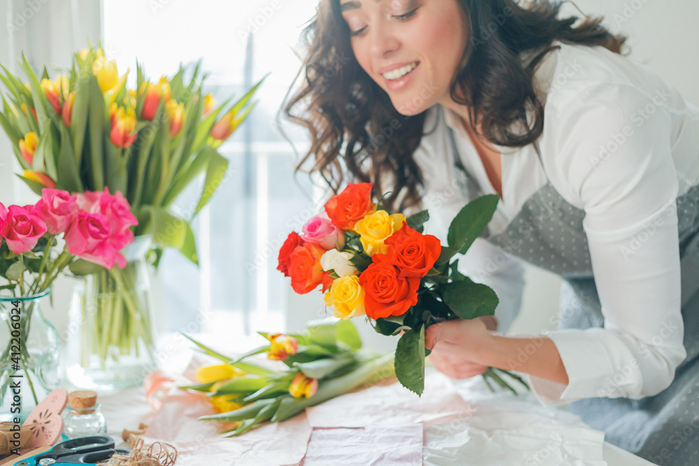 Emotional portrait of a young beautiful woman florist with dark curly hair, collects a bouquet of multicolored tulips. Small business. Spring holidays. Mothers Day. Women's Day. Emotional portrait of a young beautiful woman florist with dark curly hair, collects a bouquet of multicolored tulips. Small business. Spring holidays. Mothers Day. Women's Day.