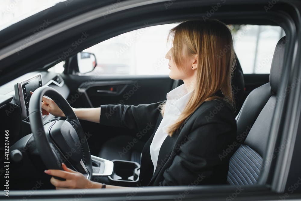 Young beautiful woman showing her love to a car in a car showroom Young beautiful woman showing her love to a car in a car showroom