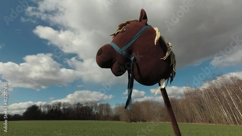 Plush vintage hobby horse toy with stick on agriculture field and clouds motion, time lapse
