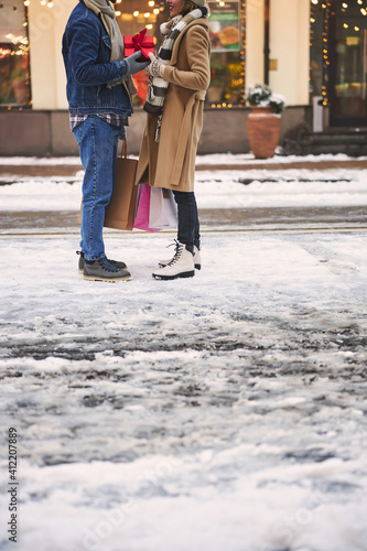 Caring man and woman exchanging Christmas presents outdoors