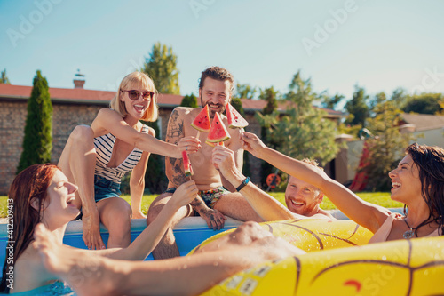 Friends making a toast with watermelon popsicles by the swimming pool © Impact Photography