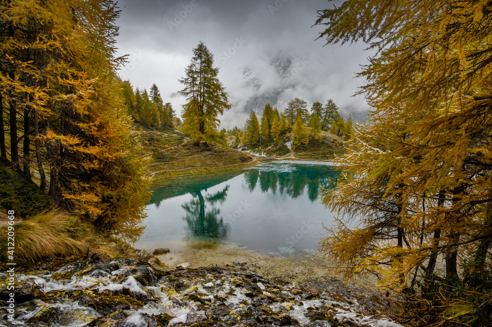 Obraz premium autumn larch at a blue mountain lake in Valais