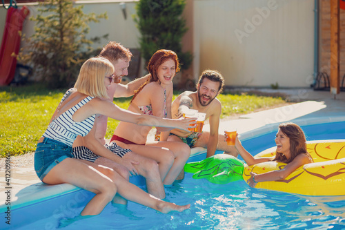 Friends making a toast while having fun at the swimming pool
