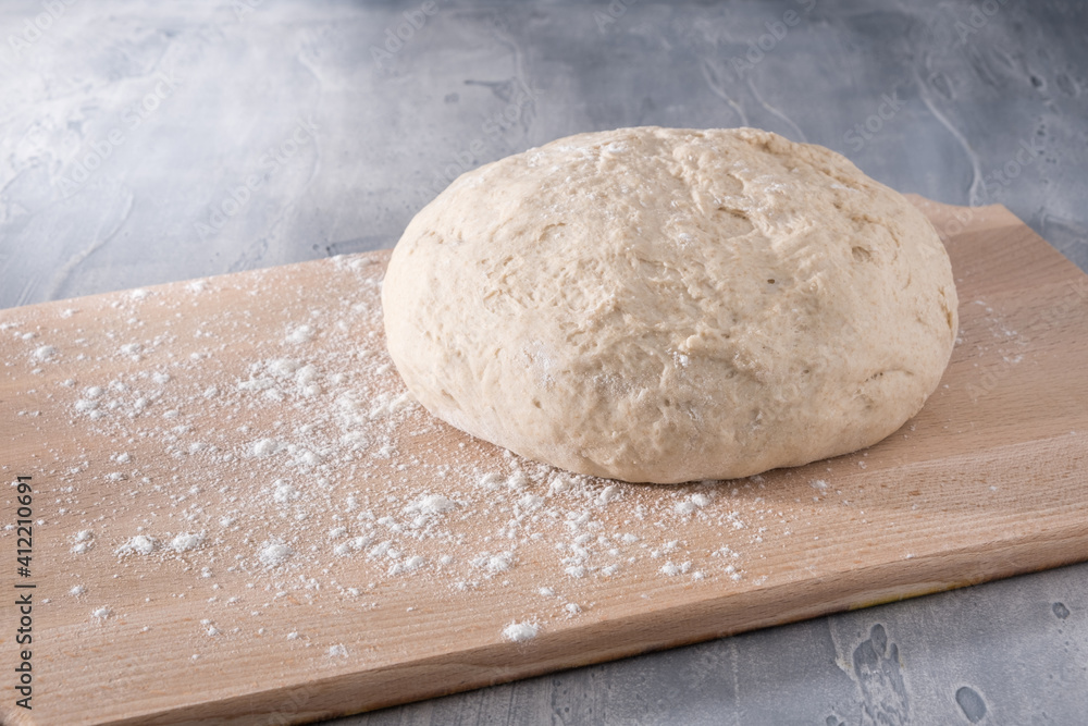 Fresh whole grain wheat dough ready for baking bread or pizza on wooden board with flour. Fresh whole grain wheat dough ready for baking bread or pizza on wooden board with flour.